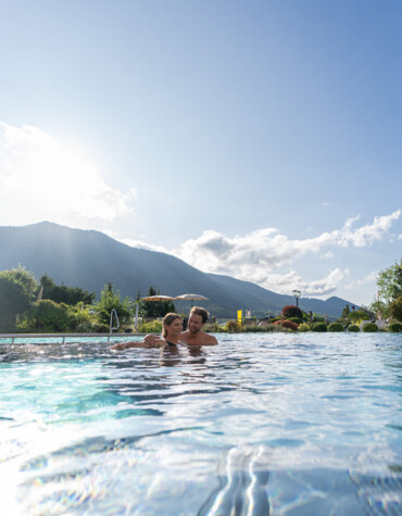 Pärchen im Außenpool des Wellnesshotel Ebner's Waldhof am See.