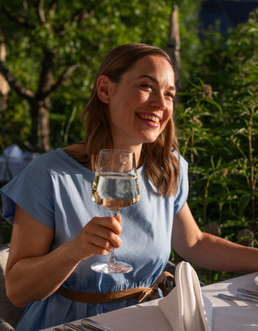 Junge Dame mit Weinglass auf der Terrasse im Hotel Ebner's Waldhof am Fuschlsee.